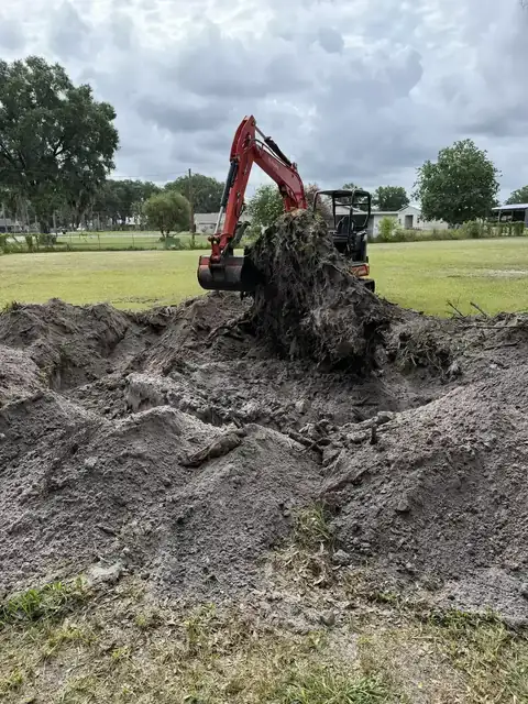 Equipment removing brush and root material during acreage cleanup