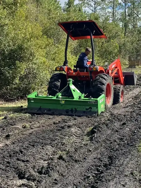 Kubota tractor with box blade leveling ground after brush clearing and cleanup