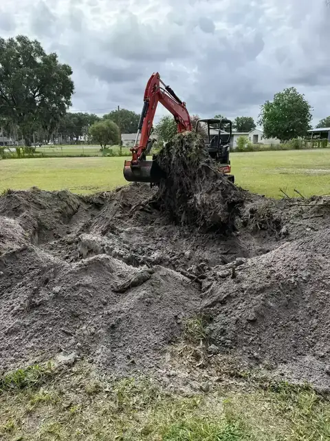 Equipment removing brush and root material during acreage cleanup