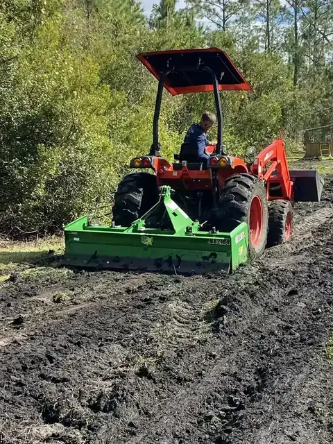 Kubota tractor with box blade leveling ground after brush clearing and cleanup